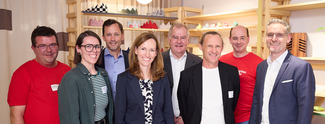 Gruppenfoto bei der Neueröffnung von „kunst.hand.werk“ in Wiener Neustadt: Acht Personen stehen in den Verkaufsräumen des Shops vor Holzregalen mit handgefertigten Produkten.