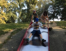 Kinder nutzen eine breite Rutsche auf einem Spielplatz im Donaupark und verbringen gemeinsam Zeit im Freien.