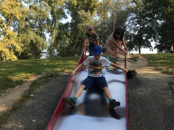Kinder nutzen eine breite Rutsche auf einem Spielplatz im Donaupark und verbringen gemeinsam Zeit im Freien.