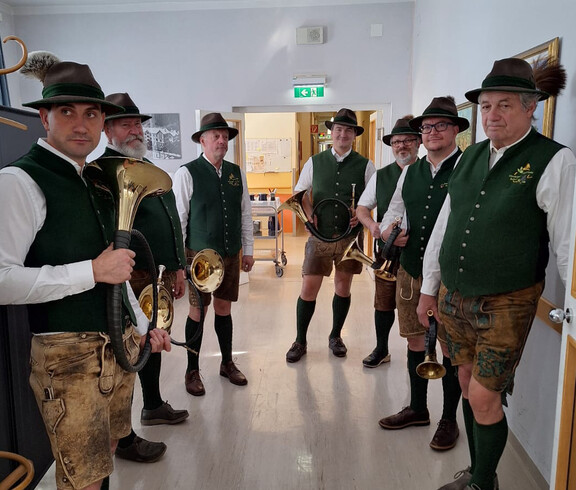 Gruppe Jagdhornbläser in Tracht mit Instrumenten in einem Flur des Pflegewohnhauses