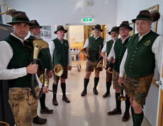 Gruppe Jagdhornbläser in Tracht mit Instrumenten in einem Flur des Pflegewohnhauses