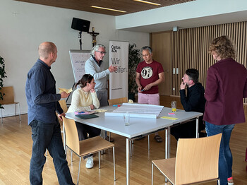 Teilnehmende diskutieren beim Caring Community Netzwerktreffen der RegionalCaritas St. Veit an einem Arbeitstisch.