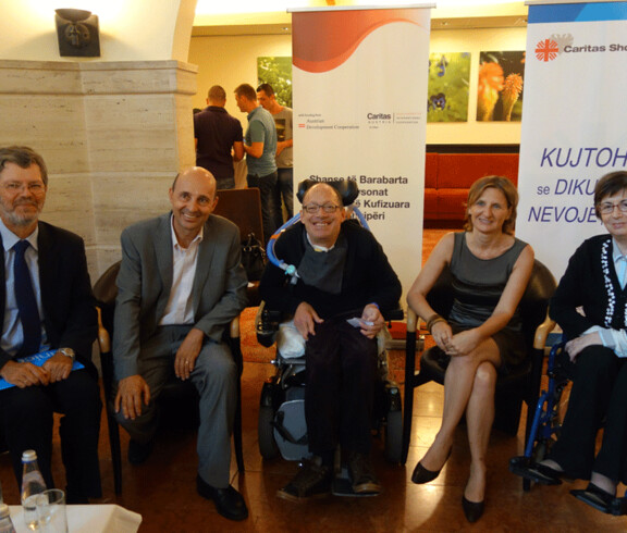 Eine Gruppe von fünf Personen, darunter ein Mann im Rollstuhl, posiert bei einer inklusiven Veranstaltung in Albanien.