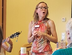 Eine Mitarbeiterin gestaltet gemeinsam mit den Bewohner*innen im Rahmen des Tags der Demenz ein musikalisches Angebot mit Gesang und Begleitung durch Gitarrenmusik.