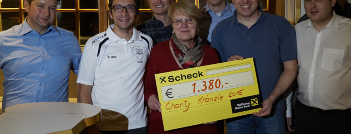 Sieben Leute versammeln sich für ein Gruppenfoto. Eine Frau und ein Mann halten einen Check in die Kamera.
