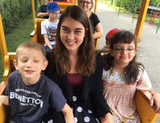 Mehrere Kinder und Begleitpersonen sitzen in den Wagen einer Parkeisenbahn und genießen gemeinsam die Fahrt durch den Donaupark.