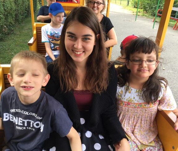 Mehrere Kinder und Begleitpersonen sitzen in den Wagen einer Parkeisenbahn und genießen gemeinsam die Fahrt durch den Donaupark.