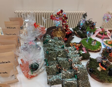 Verschiedene handgefertigte Produkte wie Kräutersalz, getrocknete Kräuter und dekorative Dioramen auf einem Tisch ausgestellt.