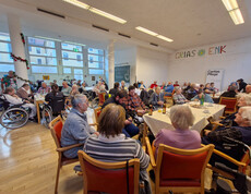 Viele Gäste sitzen an Tischen, Raum mit Weihnachtsdeko und Schriftzug „GRIAS ENK“