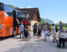 Bewohner*innen und Mitarbeitende steigen bei einem barrierefreien Reisebus aus, Rollstuhllift im Einsatz.