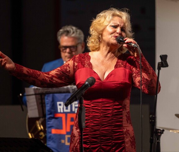 Eine Frau im roten Kleid singt auf einer Bühne