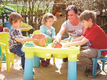 Tagesmutter beim Sandspielen mit Tageskindern