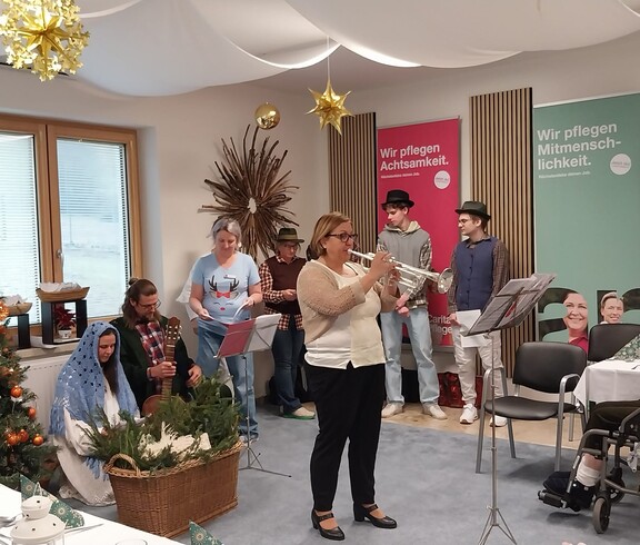 Mitarbeitende und Zivildienstleistende musizieren bei Weihnachtsfeier im festlich geschmückten Raum