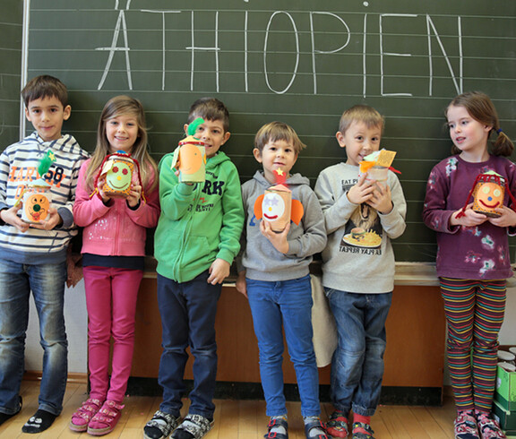 Sechs Volksschulkinder präsentieren ihre Bastelfiguren vor einer Tafel. Auf der Tafel ist mit großer Schrift Äthiopien zu lesen.