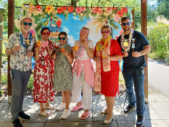 Eine Gruppe von Menschen posiert vor einem Sommerplakathintergrund.