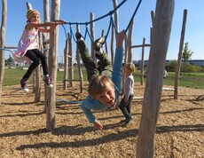 Kinder nutzen Kletter- und Hangelelemente im Motorikpark und fördern spielerisch ihre Beweglichkeit, Kraft und Koordination.