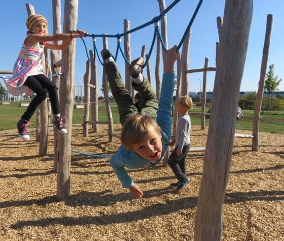 Kinder nutzen Kletter- und Hangelelemente im Motorikpark und fördern spielerisch ihre Beweglichkeit, Kraft und Koordination.