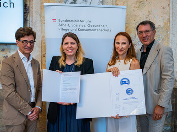 Vier Personen bei der Verleihung des Österreichischen Qualitätszertifikats ÖQZ-24 im Bundesministerium. In der Bildmitte wird die Urkunde für die Auszeichnung der Caritas Rundum Zuhause betreut im Bereich 24-Stunden-Betreuung präsentiert.