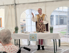 Geistlicher spricht bei der Heiligen Messe im Festzelt des Sommerfests vor den Gästen von Haus Theresia.