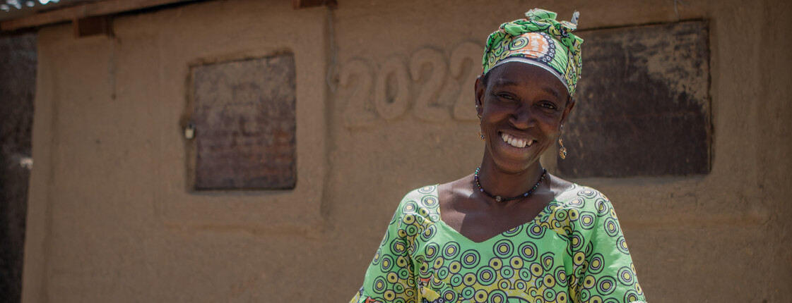 Portrait einer Frau in Mali, die traditionelle, bunte Kleidung sowie einen geflochtenen Korb trägt.