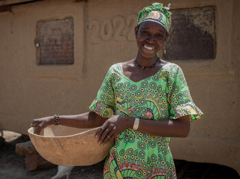 Portrait einer Frau in Mali, die traditionelle, bunte Kleidung sowie einen geflochtenen Korb trägt.
