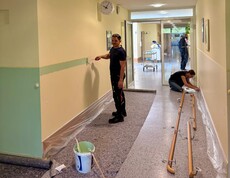 Zu sehen ist ein Gang im Pflegewohnhaus. Auf einer Seite wurde der untere Wandbereich – wie ein Sockel – bereits von der Firma Fortna GmbH in Mintgrün ausgemalt. Die gegenüberliegende Seite wird noch abgeklebt und wartet auf den nächsten Arbeitsschritt.