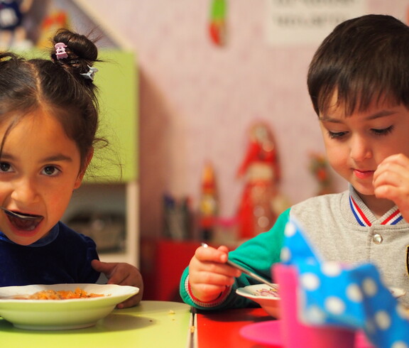 Zwei Kindergartenkinder essen eine warme Gemüsesuppe