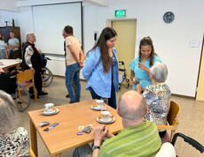 Junge Frauen im Gespräch mit Senior*innen bei Kaffee im Pflegewohnhaus Haus Franziskus