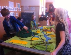 Kinder gestalten gemeinsam ein großes Landschaftsmodell mit Flüssen, Wegen und Gebäuden und erkunden spielerisch ökologische Zusammenhänge.