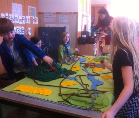 Kinder gestalten gemeinsam ein großes Landschaftsmodell mit Flüssen, Wegen und Gebäuden und erkunden spielerisch ökologische Zusammenhänge.