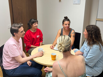 Junge Frauen sitzen gemeinsam an einem runden Tisch und unterhalten sich.