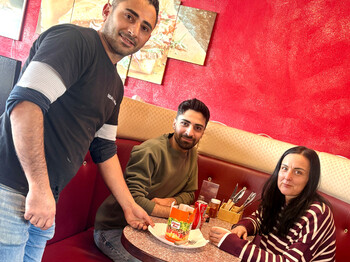 Eine Frau und ein Mann bekommen von einem Kellner einen Kebap serviert.