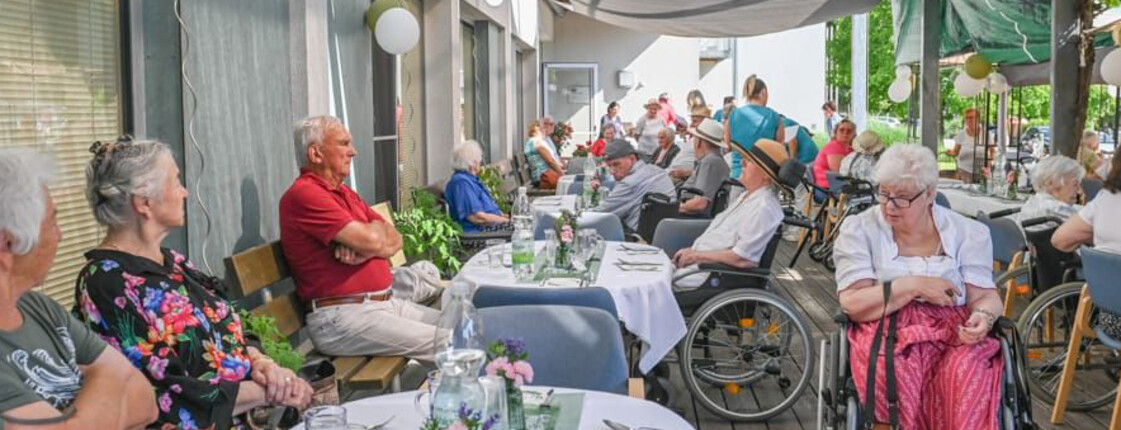 Festlich gedeckte Terrasse mit Gästen und Bewohner*innen beim Sommerfest im Haus Maria.