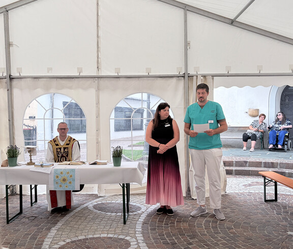 Andacht im Festzelt des Sommerfests im Haus Theresia mit Geistlichem und zwei Mitarbeitenden vor dem Altar.
