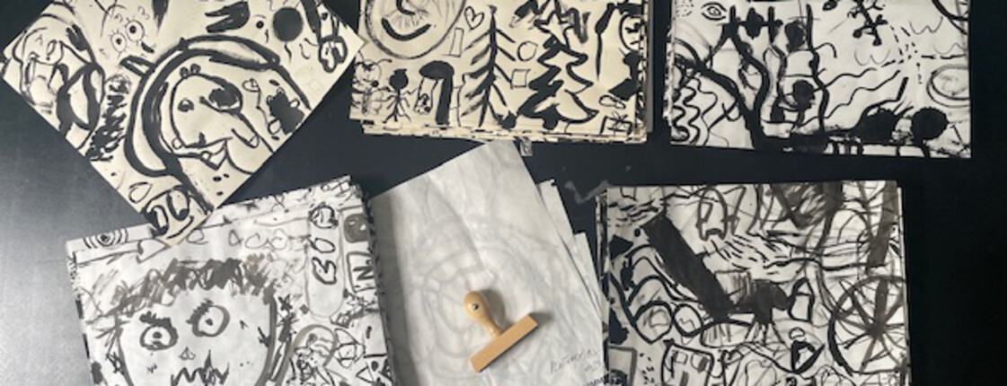 Mehrere schwarz-weiße Druckgrafiken mit fantasievollen Zeichnungen liegen auf einem Tisch. Die Arbeiten entstanden im kreativen Kunstunterricht.