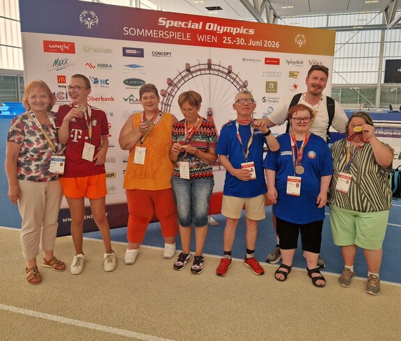 Mannschaft mit Medaillen in der Sporthalle