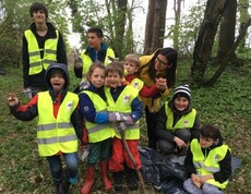 Kinder und Begleitpersonen sammeln im Rahmen eines Waldputztags Abfälle in der Natur und setzen sich gemeinsam für Umweltschutz ein.