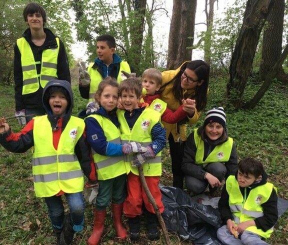 Kinder und Begleitpersonen sammeln im Rahmen eines Waldputztags Abfälle in der Natur und setzen sich gemeinsam für Umweltschutz ein.