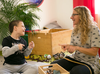 Frau und Kind sitzen am Boden und spielen gemeinsam