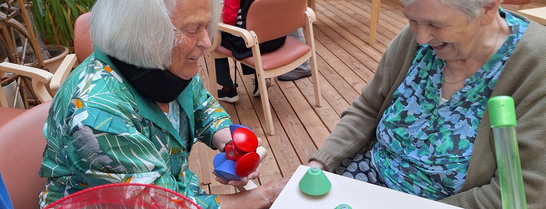 Zwei Bewohnerinnen eines Pflegewohnhauses sitzen an einem Tisch und beschäftigen sich im Rahmen einer Aktion zum Tag der Demenz mit bunten Spiel- und Bewegungsmaterialien.