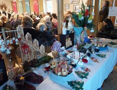 Tisch mit handgefertigten Weihnachtsartikeln, Besucher*innen im Hintergrund