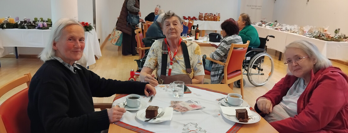 Bewohner*innen des Pflegewohnhauses St. Hemma Haus in Friesach beim Weihnachtsbasar, umgeben von festlicher Dekoration und Weihnachtsstimmung.