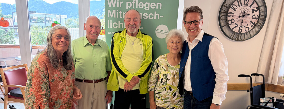 Bewohner*innen stehen im Haus Theresia um einen Tisch mit historischen Alltagsgegenständen beim Erinnerungscafé.