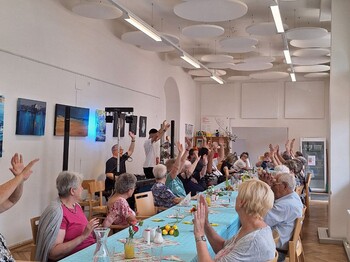 Senior:innen an einem Tisch setzen und singen zusammen