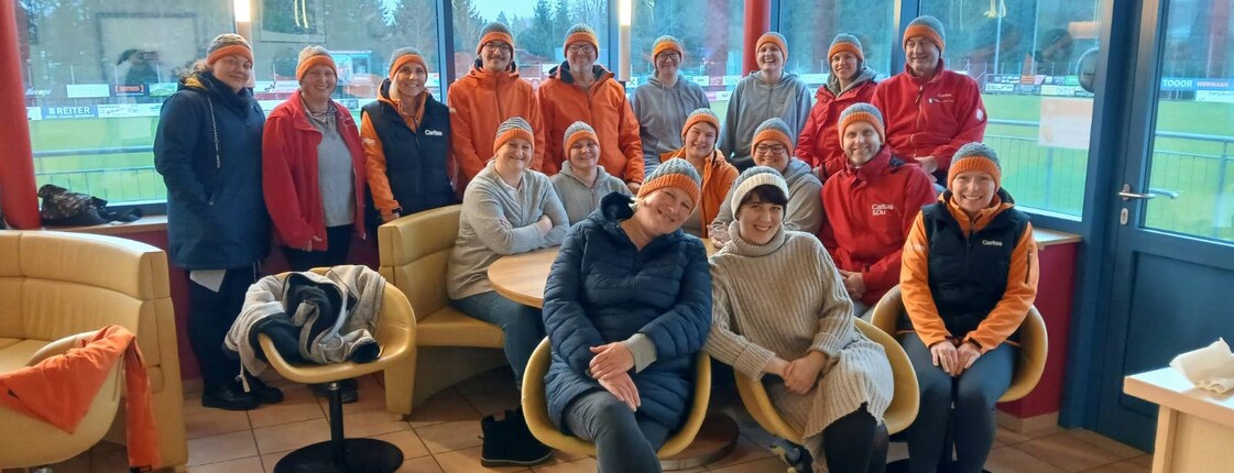 Das Team der mobilen Pflegedienste mit selbst gestrickten Hauben einer zufriedenen Kundin