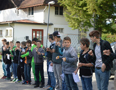 Viele Kinder stehen hinter einem Zaun im Freien.