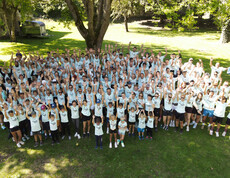 Große Laufgruppe in einheitlichen Shirts, der HT Running Crew, versammelt sich für ein Gruppenfoto im Park.