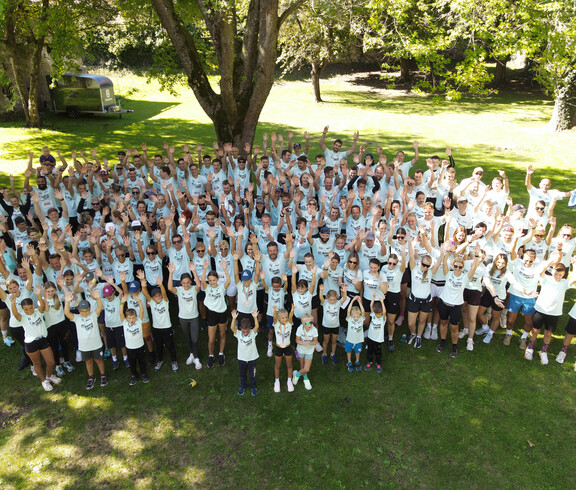 Große Laufgruppe in einheitlichen Shirts, der HT Running Crew, versammelt sich für ein Gruppenfoto im Park.