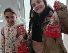Zwei Kinder zeigen fröhlich ihre Nikolausgeschenke in die Kamera.