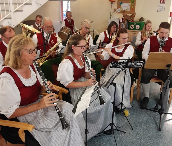 Die Marktmusikkapelle Lannach sitzt in Formation und spielt live im Pflegewohnhaus. Die Musiker tragen ihre traditionellen Uniformen.